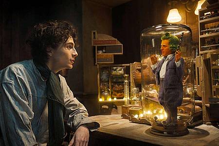 Timothee Chalamet (l) als Willy Wonka und Hugh Grant als Oompa Loompa in einer Szene des Films "Wonka".