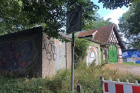 altes umwuchertes Gebäude und Garage mit gemaltem Regenbogen auf dem Tor