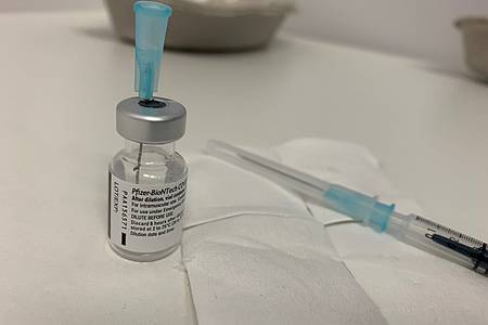 Kanüle steckt in Impfampulle daneben Einwegspritze