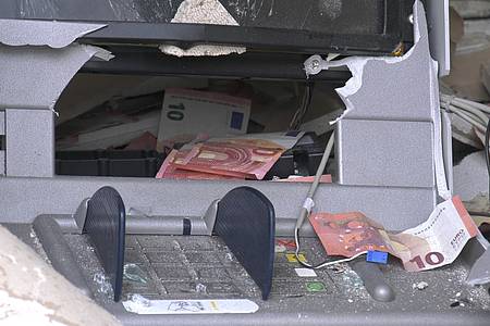 Geldscheine hämngen aus dem Ausgabeschacht eines gesprengten Geldautomaten