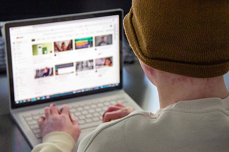 Junger Mann schaut auf Laptop mit youtube geöffnet