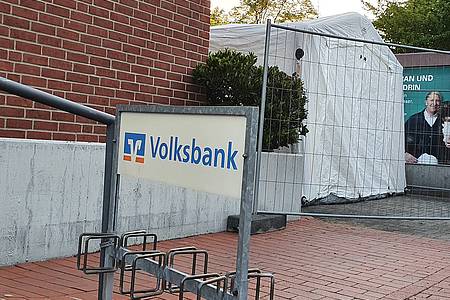 Bauzaun und Zelt neben einem Gebäude, Fahrradständer mit Aufschrit "Volksbank"